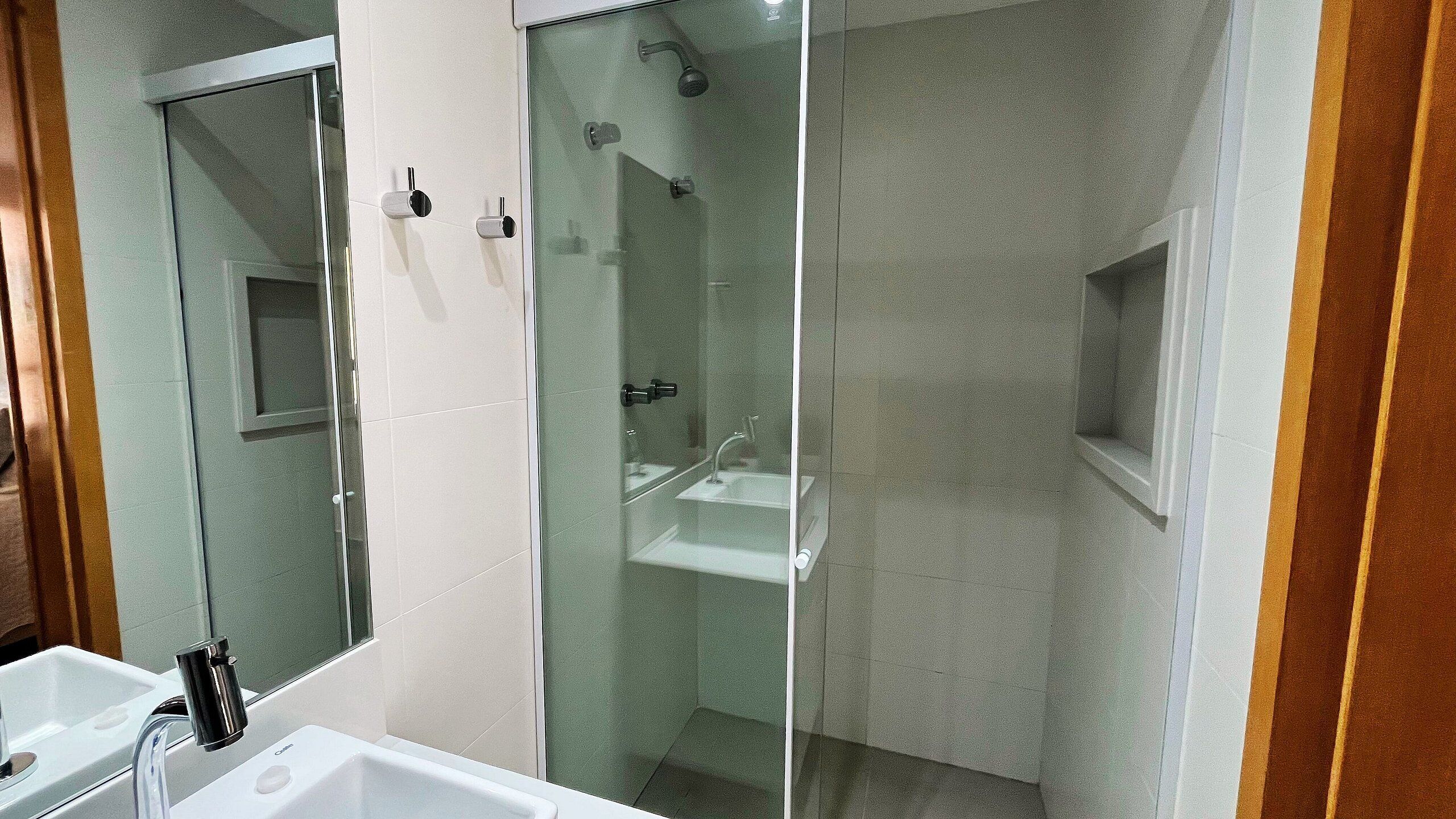 Ein Badezimmer mit einer Duschkabine, einem Waschbecken und einem Spiegel.