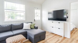 Een moderne woonkamer met een grijze modulaire bank, een flatscreen televisie en een witte kast.