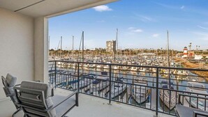 A balcony with a view of a marina, featuring several boats and a lighthouse. - Serene Harborfront Condo | Unbeatable Views & Coastal Charm (Oceanside)