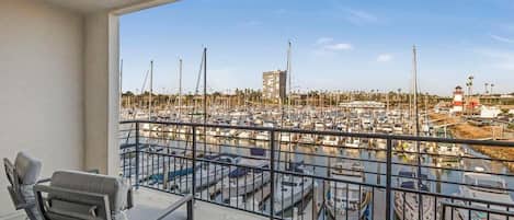 A balcony with a view of a marina, featuring several boats and a lighthouse.