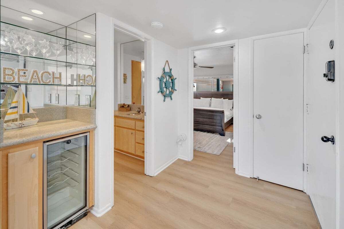 A modern kitchen with a glass-fronted refrigerator, wooden cabinets, and a countertop with a decorative sailboat.