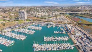Un port de plaisance où sont amarrés de nombreux bateaux, un espace de stationnement et un pont en arrière-plan.