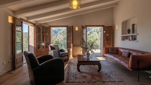 Ein geräumiges Wohnzimmer mit großem Fenster, einem Ledersofa, einem Couchtisch und einem Bücherregal.