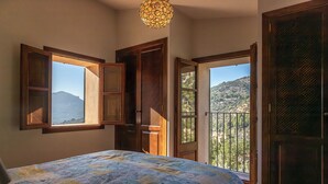 Ein Schlafzimmer mit einem Bett, einem Fenster und einer Tür, die auf einen Balkon führt.