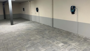 Eine Parkgarage mit Fliesenböden und -wänden, ausgestattet mit Ladestationen für Elektrofahrzeuge.