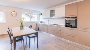 Eine moderne Küche mit hellen Holzschränken, einem eingebauten Backofen und einem Essbereich mit Tisch und Stühlen.