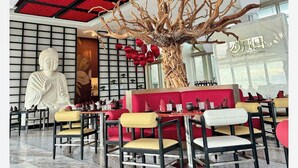 A modern interior with a large Buddha statue, red ceiling panels, and a mix of yellow and white seating. - Hotel Mousai - 2 bedroom (Cancún)
