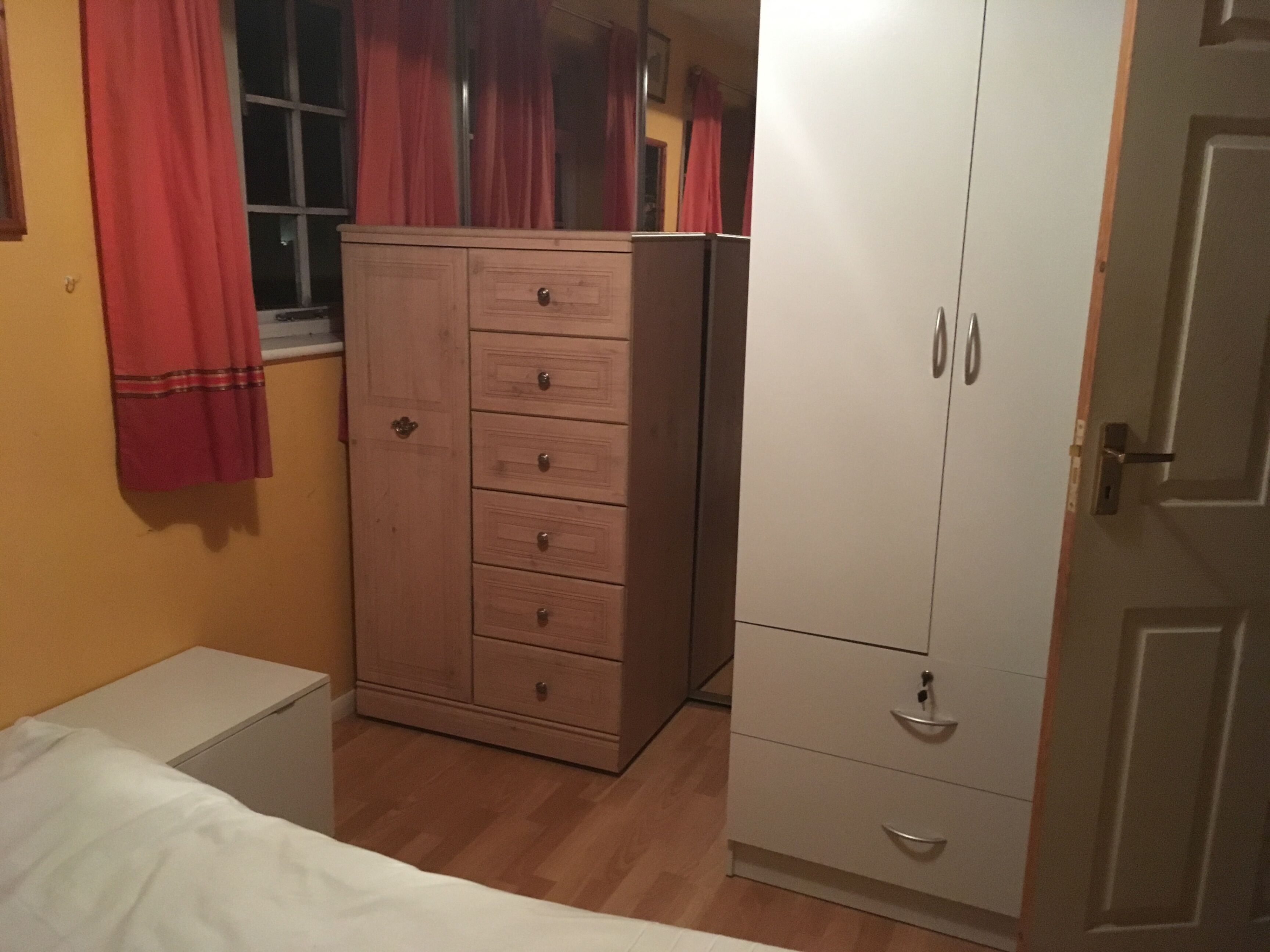 Ein Schlafzimmer mit einem Bett, einem Holzschrank und einem weißen Schrank mit zwei Türen.