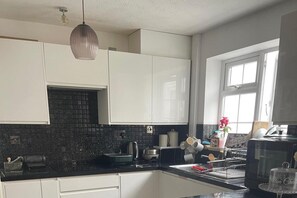 A modern kitchen with white cabinets, a black backsplash, and a window providing natural light. - Cardiff House With 3 Bedrooms (Cardiff)