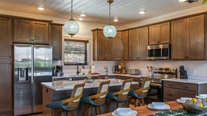 Una cocina moderna con electrodomésticos de acero inoxidable, armarios de madera y una isla central con taburetes de bar.