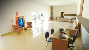 Un área de espera moderna con un mostrador de recepción, varias sillas y un cartel grande en la pared.
