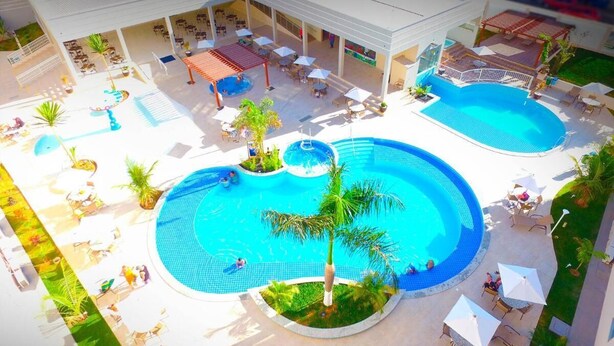 Un resort con dos piscinas amplias, zonas de estar al aire libre y un patio cubierto.