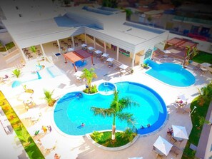 Ein Resort mit zwei großen Schwimmbecken, Außenbereichen mit Sitzgelegenheiten und einer überdachten Terrasse.