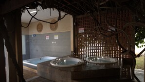 Un área de spa con dos jacuzzis bajo una estructura de madera.