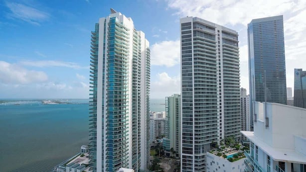 A high-rise building with multiple balconies, a rooftop pool, and a view of the ocean. - The Noir Suite 3BR 2BTH Glam Room PS5 Pool Gym (Miami)
