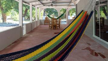 A covered outdoor area with a hammock, chairs, and a table.