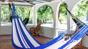 A hammock in a covered outdoor area with wooden chairs and a view of greenery.