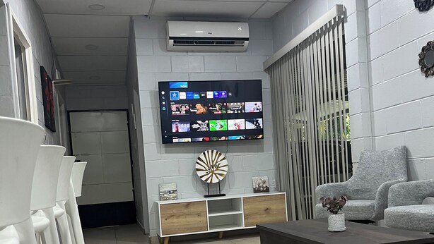 A modern living room with a flat-screen TV mounted on the wall, a coffee table, and a sofa.