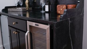 A kitchen with a black countertop, stainless steel appliances, a decorative mirror, and a potted plant.