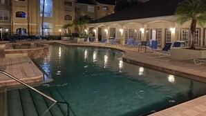 Ein Hotelpoolbereich mit Liegestühlen und einem Gebäude mit mehreren Balkonen.