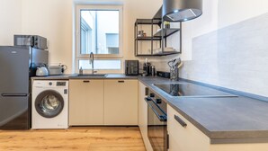 A compact kitchen with a washing machine, a sink, and a coffee machine. - Studio Augusta: modern, fully equipped, Rhine 50m, business & private, all-inclusive (Koblenz)