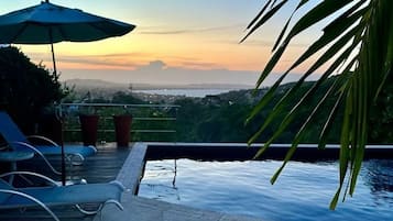 Piscina no terraço com vista para a cidade ao pôr do sol.