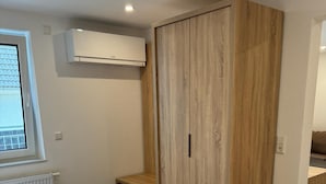 Un dormitorio con cama, armario, radiador y ventana.