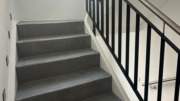 Una escalera con barandilla de metal y una ventana en lo alto.