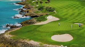A golf course with a sandy bunker, palm trees, and a view of the ocean. - Cap Cana Luxury 2 bedroom and 2 bath condo, Pool, near Juanillo beach, Golf




 (Las Canas)