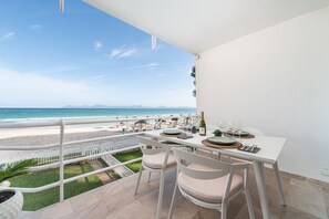 Eine Terrasse mit Esstisch, mit Blick auf Strand und Meer.