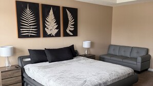 A bedroom with a bed, two nightstands, a ceiling fan, and three fern wall art pieces. - Vacation Paradise in Jonesboro (Jonesboro)