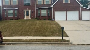 A two-story brick house with a front lawn, a driveway, and two garage doors. - Vacation Paradise in Jonesboro (Jonesboro)
