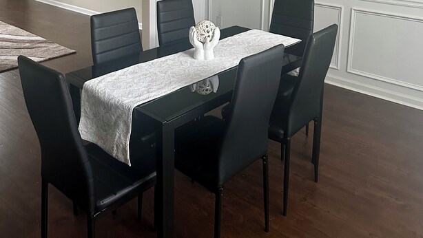 A dining area with a table set for six, surrounded by black chairs, a white tablecloth, and a decorative centerpiece. - Vacation Paradise in Jonesboro (Jonesboro)