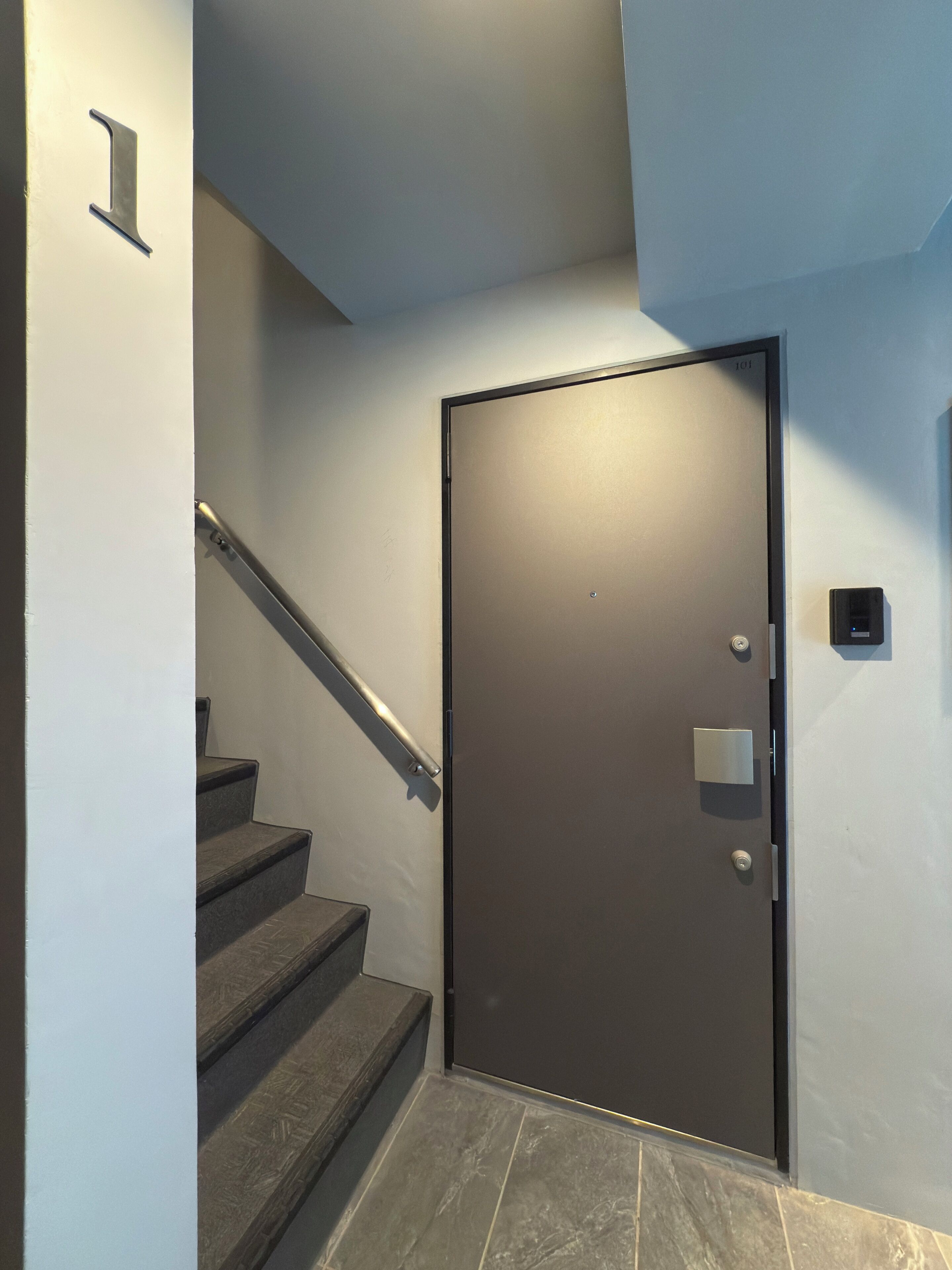 Un interior moderno con una escalera que lleva a una puerta con el número 101.