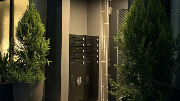 A modern building entrance with a glass door, potted plants, and a metal gate. - Tasuki Smart Kinshicho II (Tokyo)