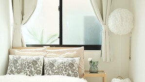 A bedroom with a bed, curtains, a hanging light, a bedside table, and a window. - Tasuki Smart Kinshicho II (Tokyo)