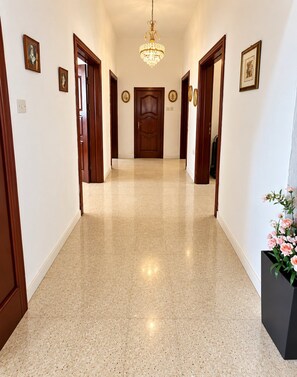 Un pasillo con piso pulido, puertas de madera y un candelabro.