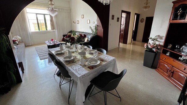 A dining area with a table set for four, a chandelier, and a view through an archway to another room. - Valletta Majestic Grand Harbour View 3-Bedroom by Malta Weekend (Valletta)