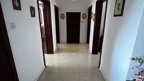 A hallway with a chandelier, framed pictures on the walls, and a door at the end. - Valletta Majestic Grand Harbour View 3-Bedroom by Malta Weekend (Valletta)