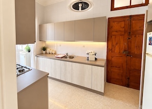 Una cocina moderna con estufa a gas empotrada, un fregadero y una puerta de madera.