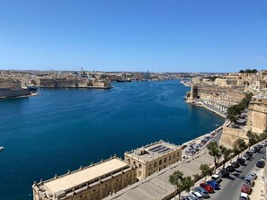 Un paisaje urbano costero con un puerto destacado, edificios históricos y un cielo azul despejado.