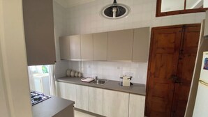 A kitchen with light-colored cabinets, a stainless steel sink, a wooden door, and a ceiling fan. - Valletta Majestic Grand Harbour View 3-Bedroom by Malta Weekend (Valletta)