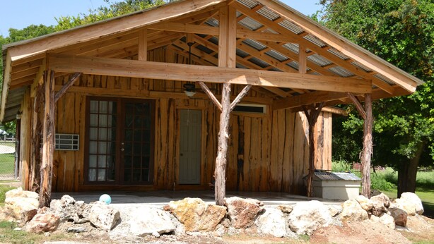 Een houten chalet met een overdekte veranda, grote ramen en een deur.