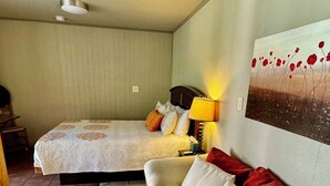 Een slaapkamer met een bed, een bank, een lamp en een schilderij aan de muur.