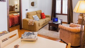 A living room with a sofa, a small table with a laptop, a lamp, and a window with curtains. - LA CASA DEL MAESTRO DE MÚSICA (Baeza)
