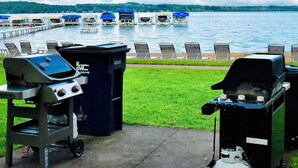 Uitzicht op een meer met een steiger, loungesessels en barbecues.
