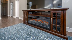 Una sala de estar con chimenea, un aparador de madera y un tapete azul estampado.