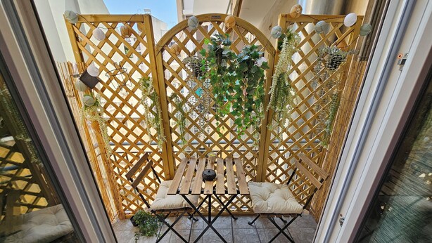A wooden lattice partition with a table and chairs in a courtyard.