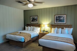 A hotel room with two beds, a ceiling fan, a nightstand with a lamp, and framed pictures on the wall. - Spacious lodge with 18 bedrooms, large living area with pool table and more! (Tulsa)