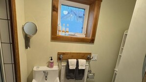 Ein Badezimmer mit Waschbecken, Spiegel, Fenster und Toilette.